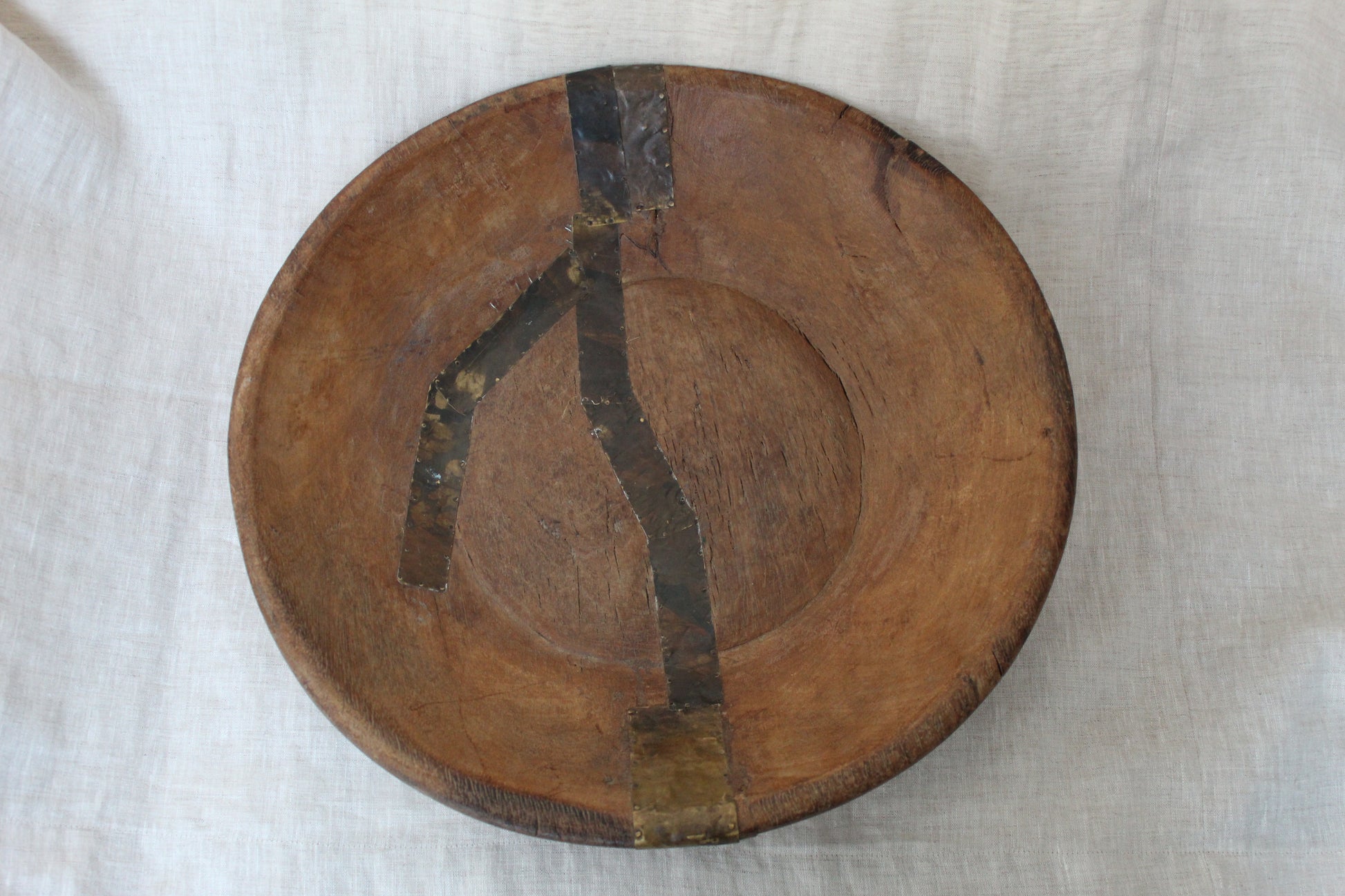 Wooden bowl with a crack on a white fabric background
