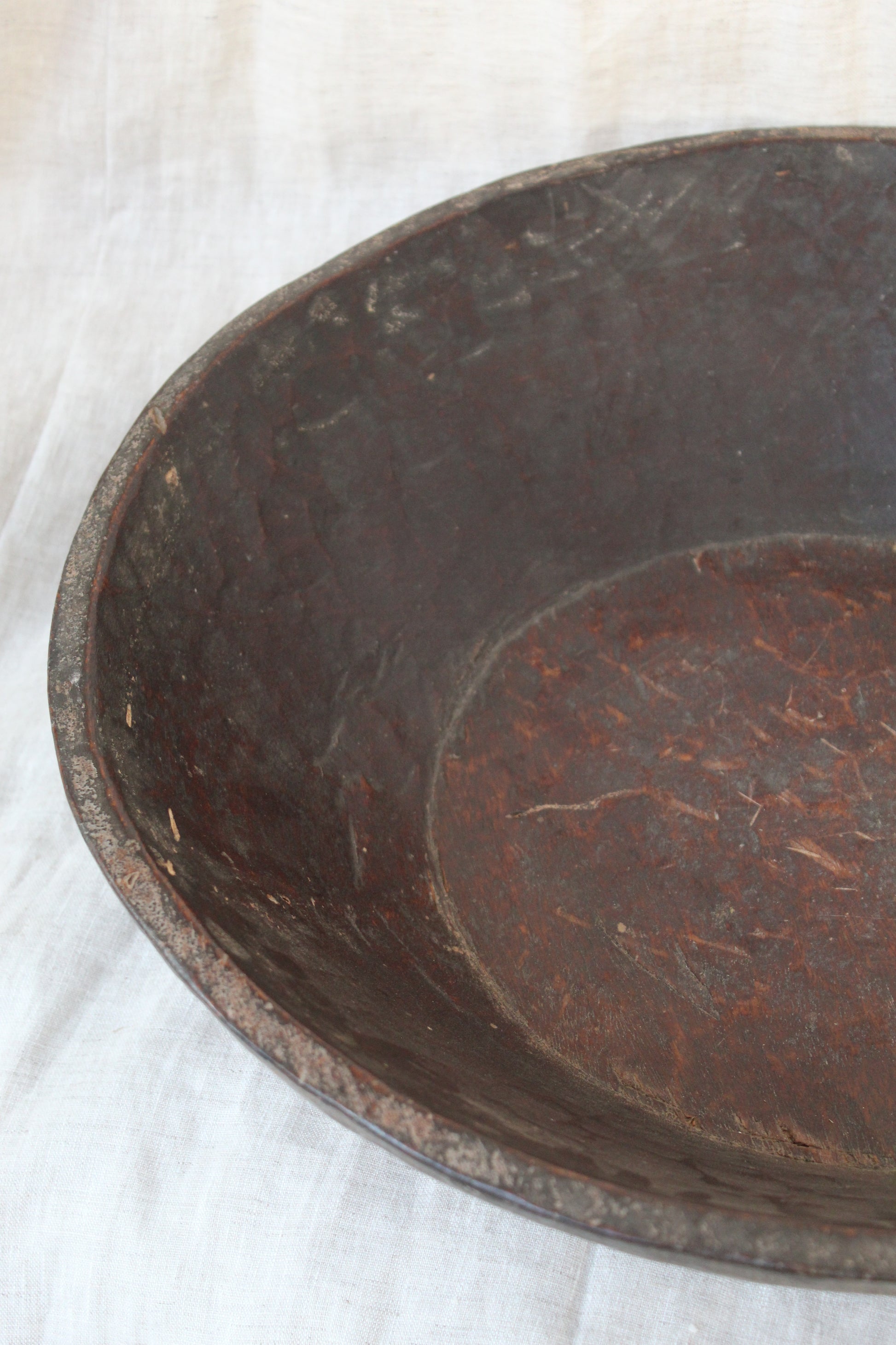 Close-up of a dark brown wood item with visible wear on a white background