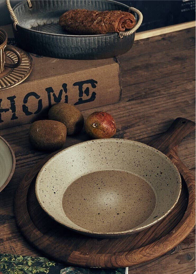Ceramic bowl on a wooden surface with 'HOME' sign and fruits in the background