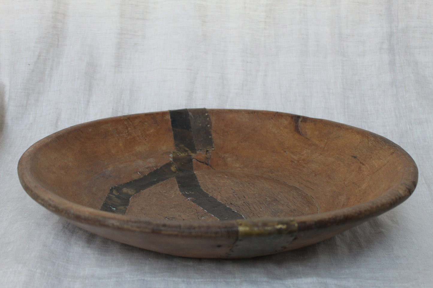 Wooden bowl with decorative design on a white fabric background