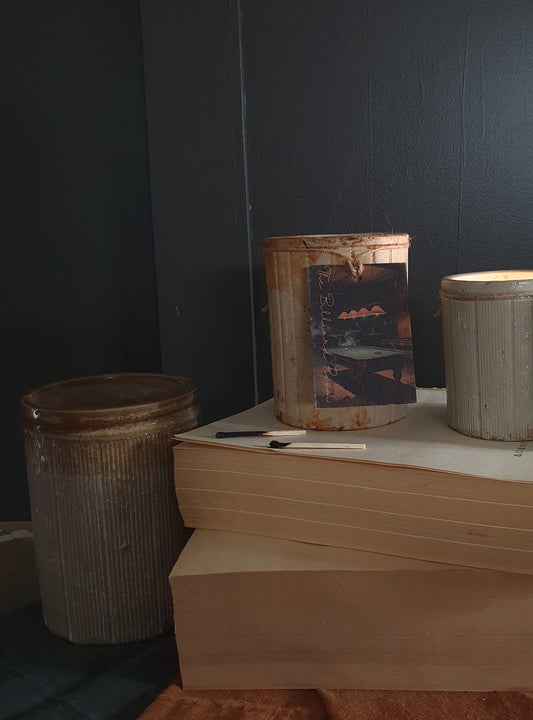 Three rustic jars on a stack of books against a dark wall.