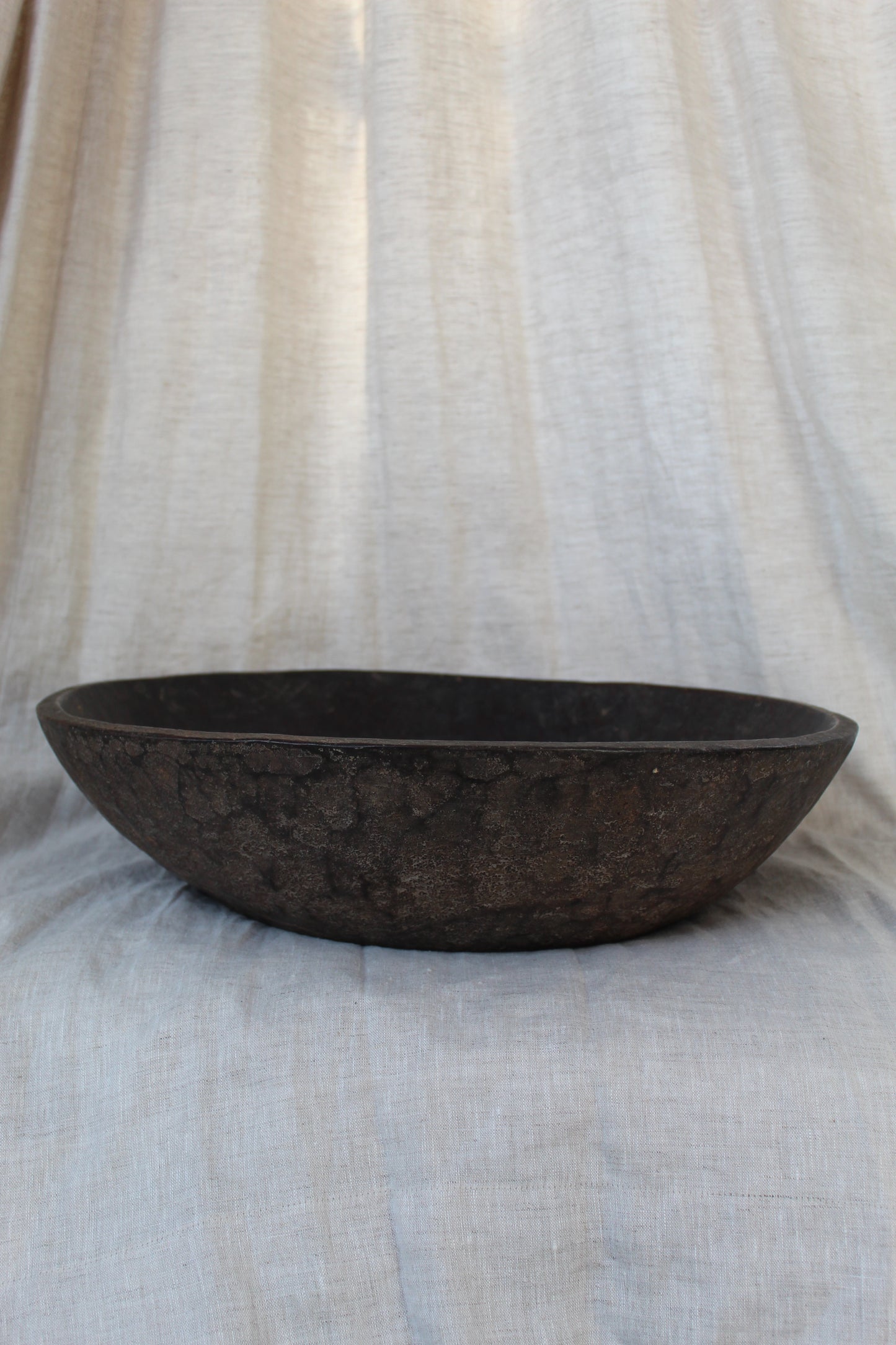 Dark brown wood on a textured white and beige fabric background