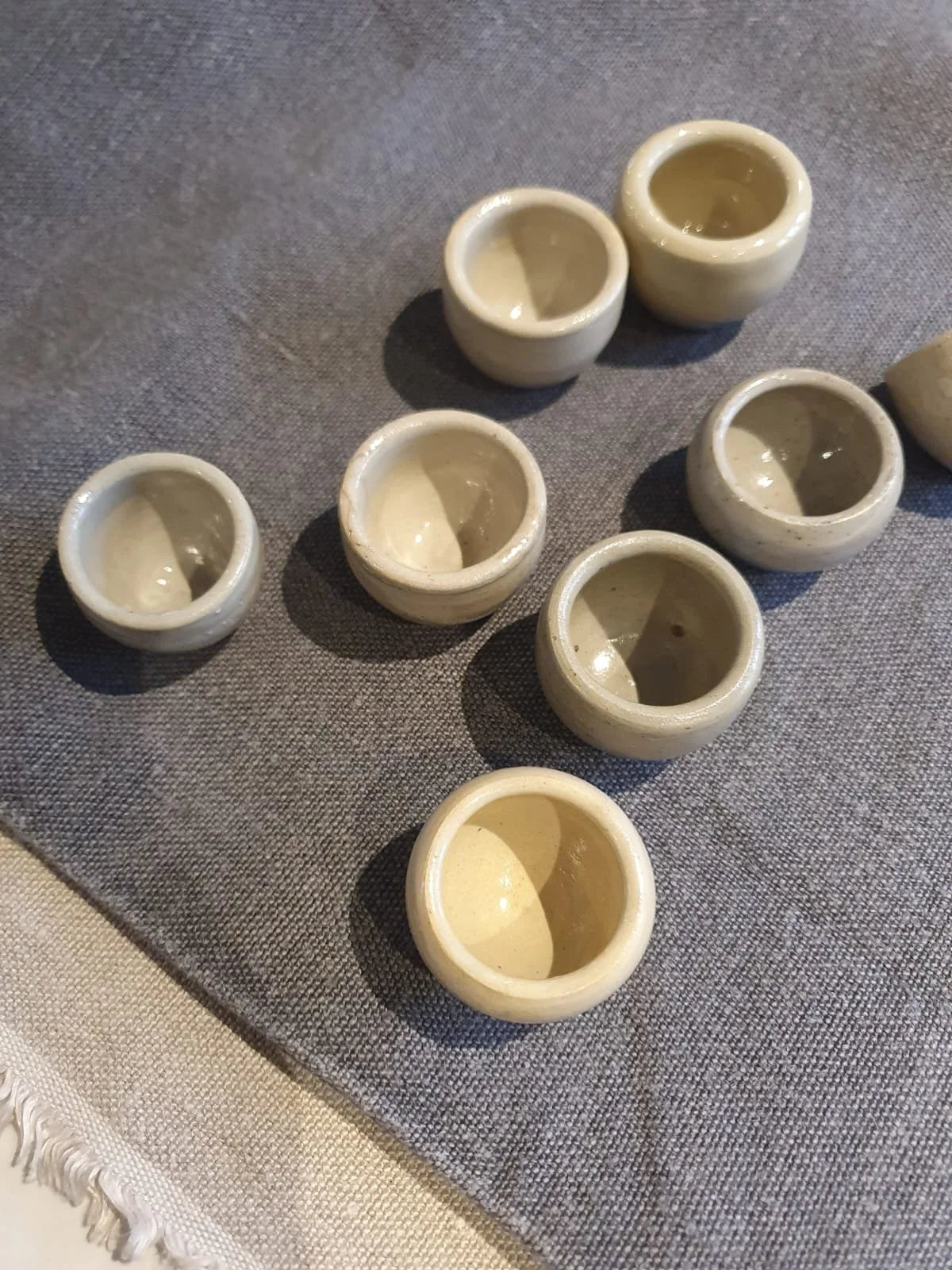 Set of small ceramic cups on a textured fabric surface