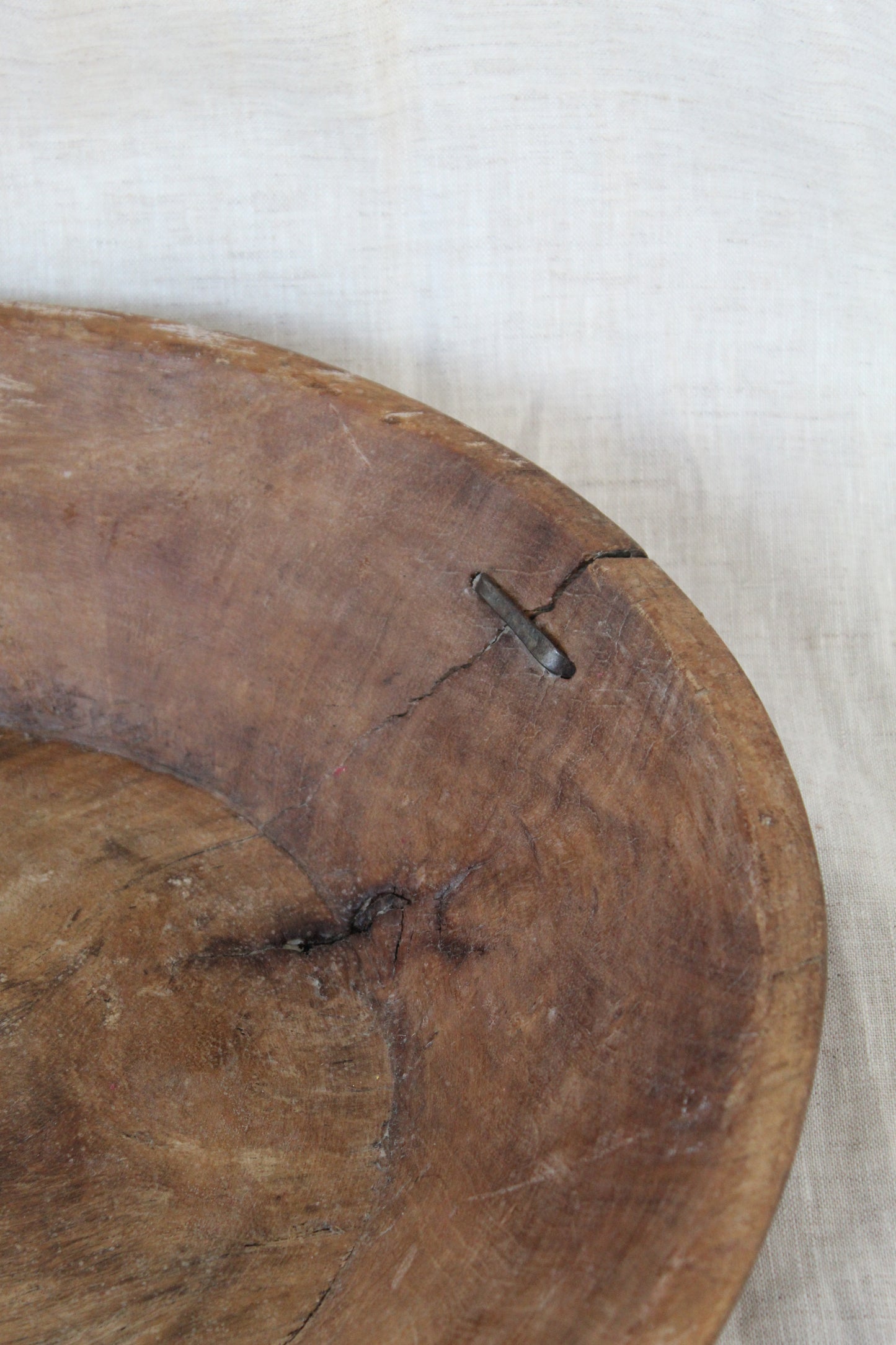 Close-up of a wooden surface with a metal object on a light fabric background