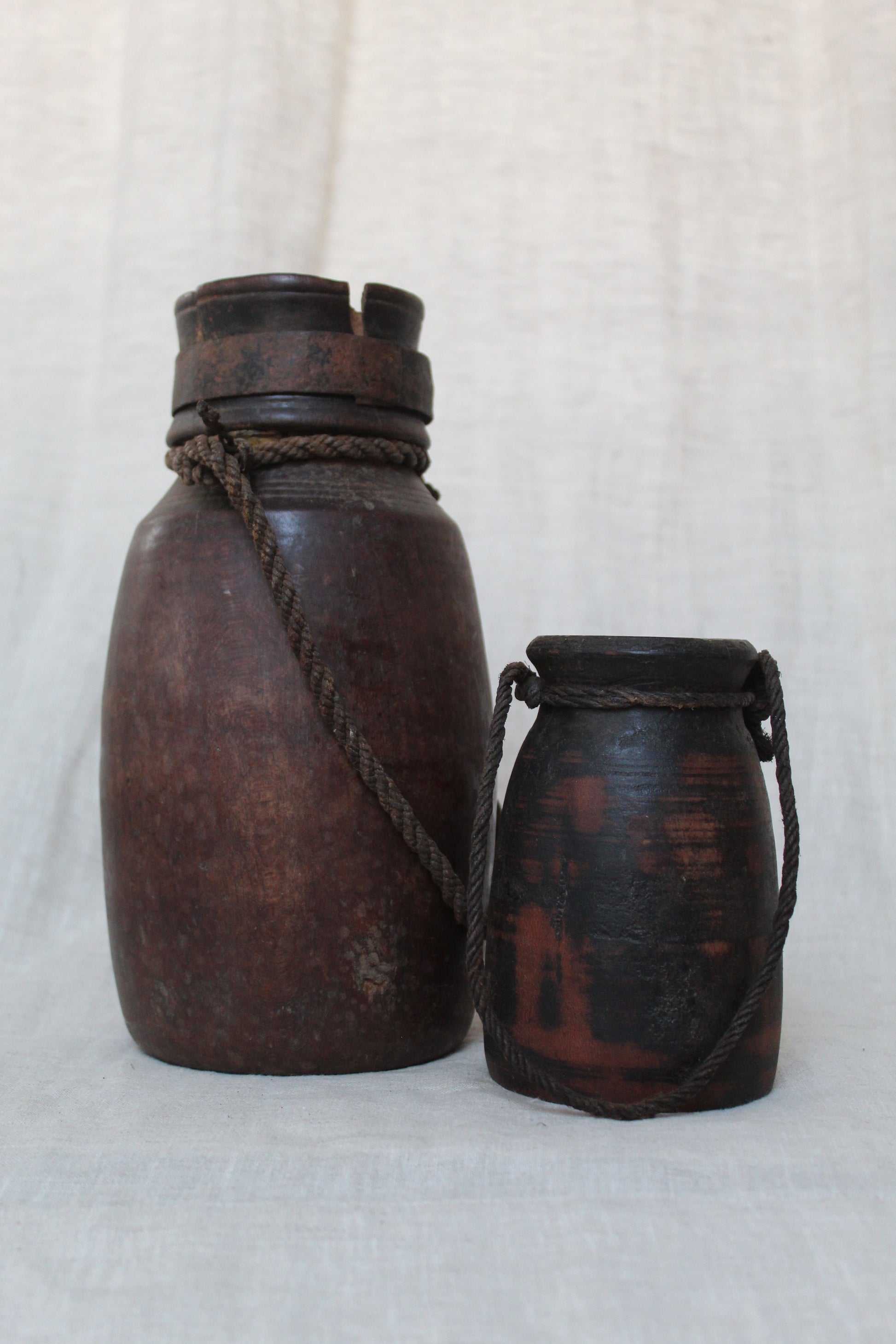 Two brown wooden bottles with rope handles on a white background