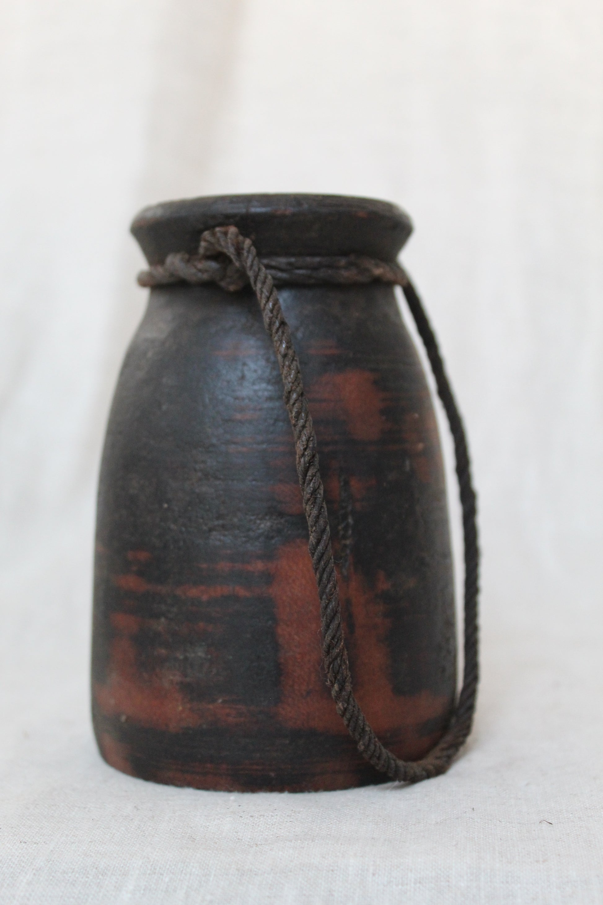 Black and red wooden container with a rope handle on a white background