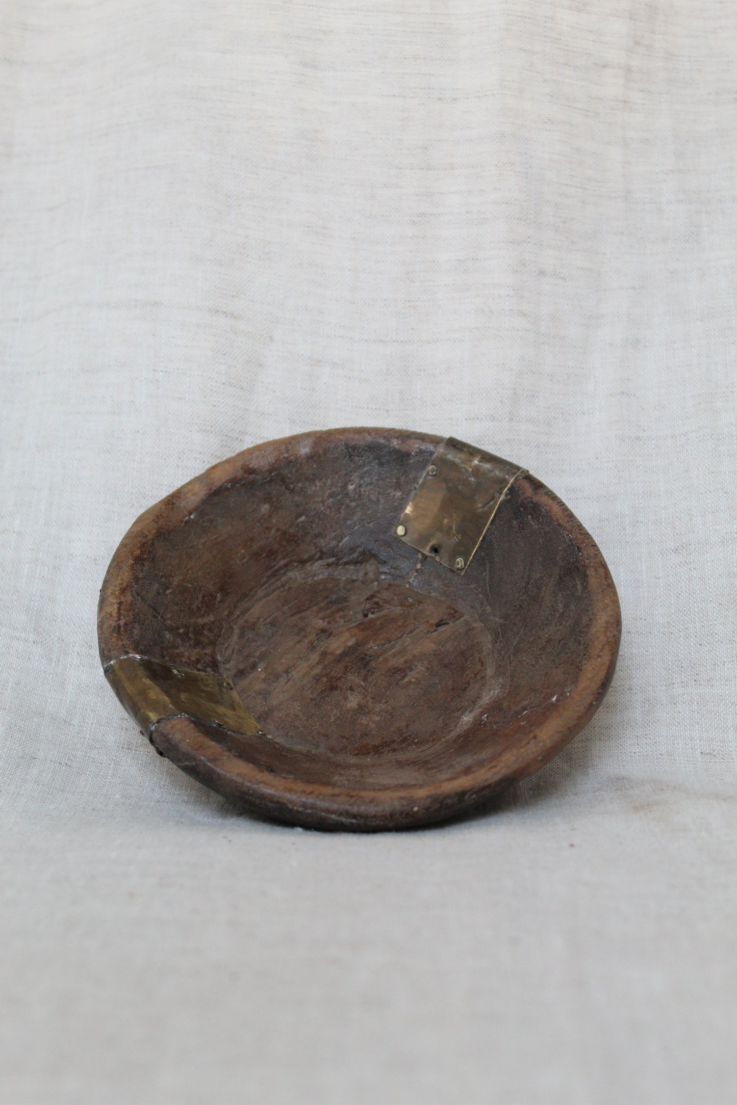 Wooden bowl with a metal clasp on a white fabric background