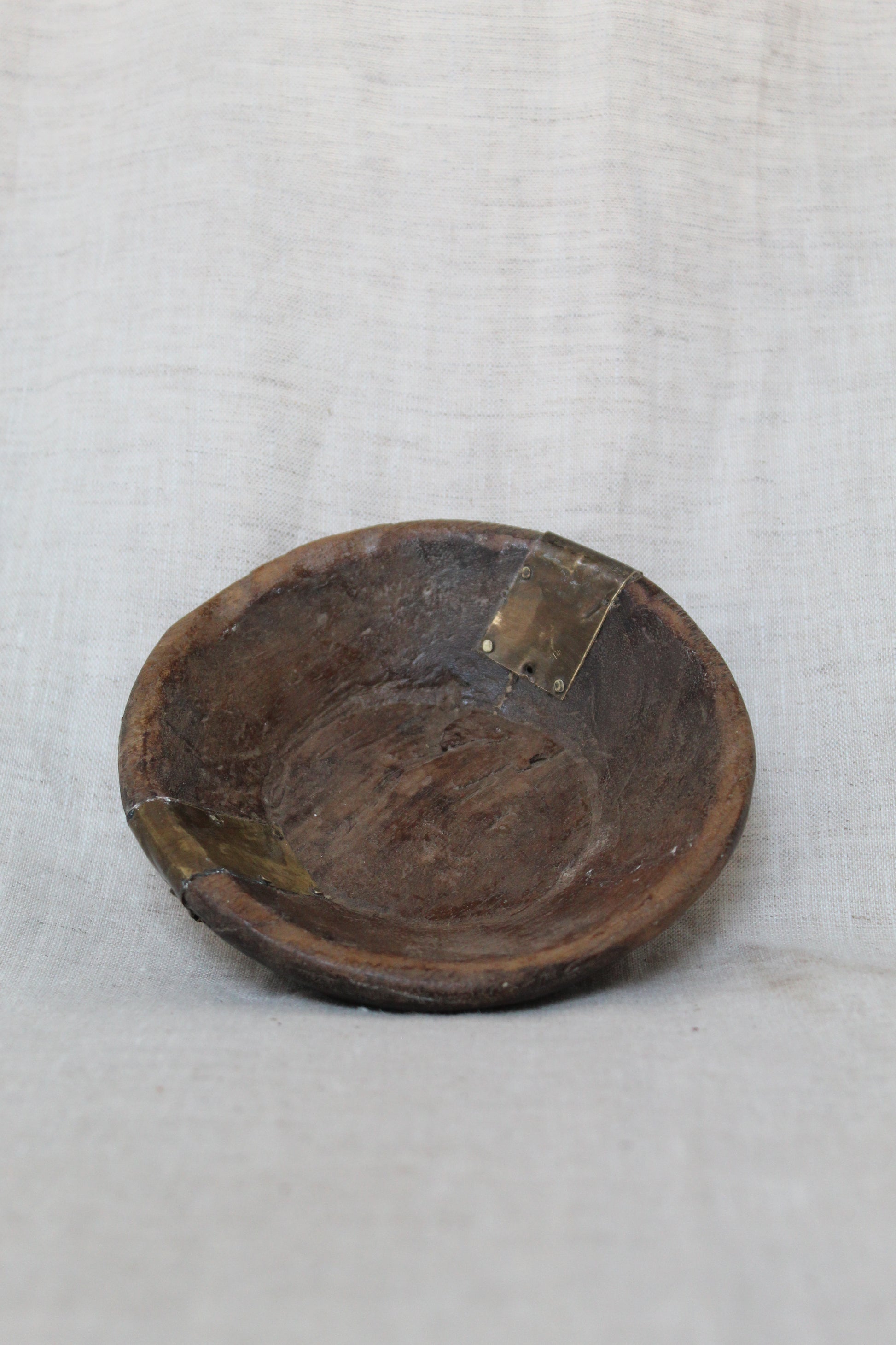 Wooden bowl with a metal clasp on a white fabric background