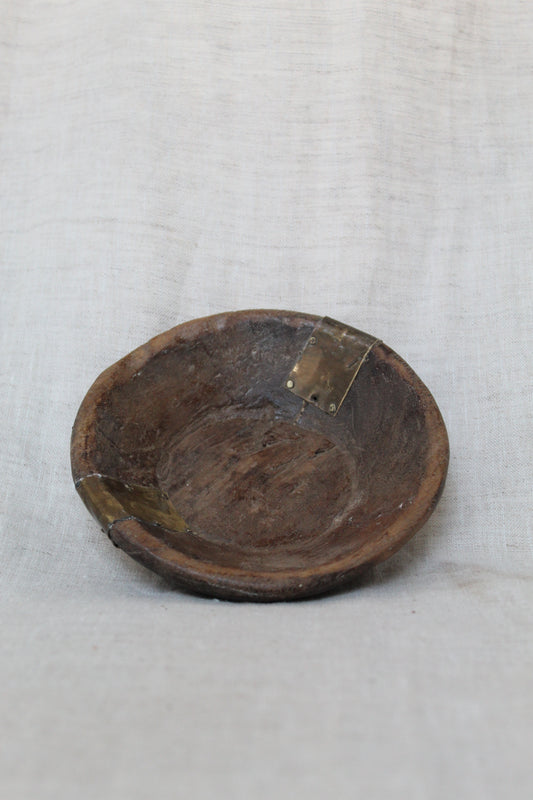 Wooden bowl with a metal clasp on a white fabric background