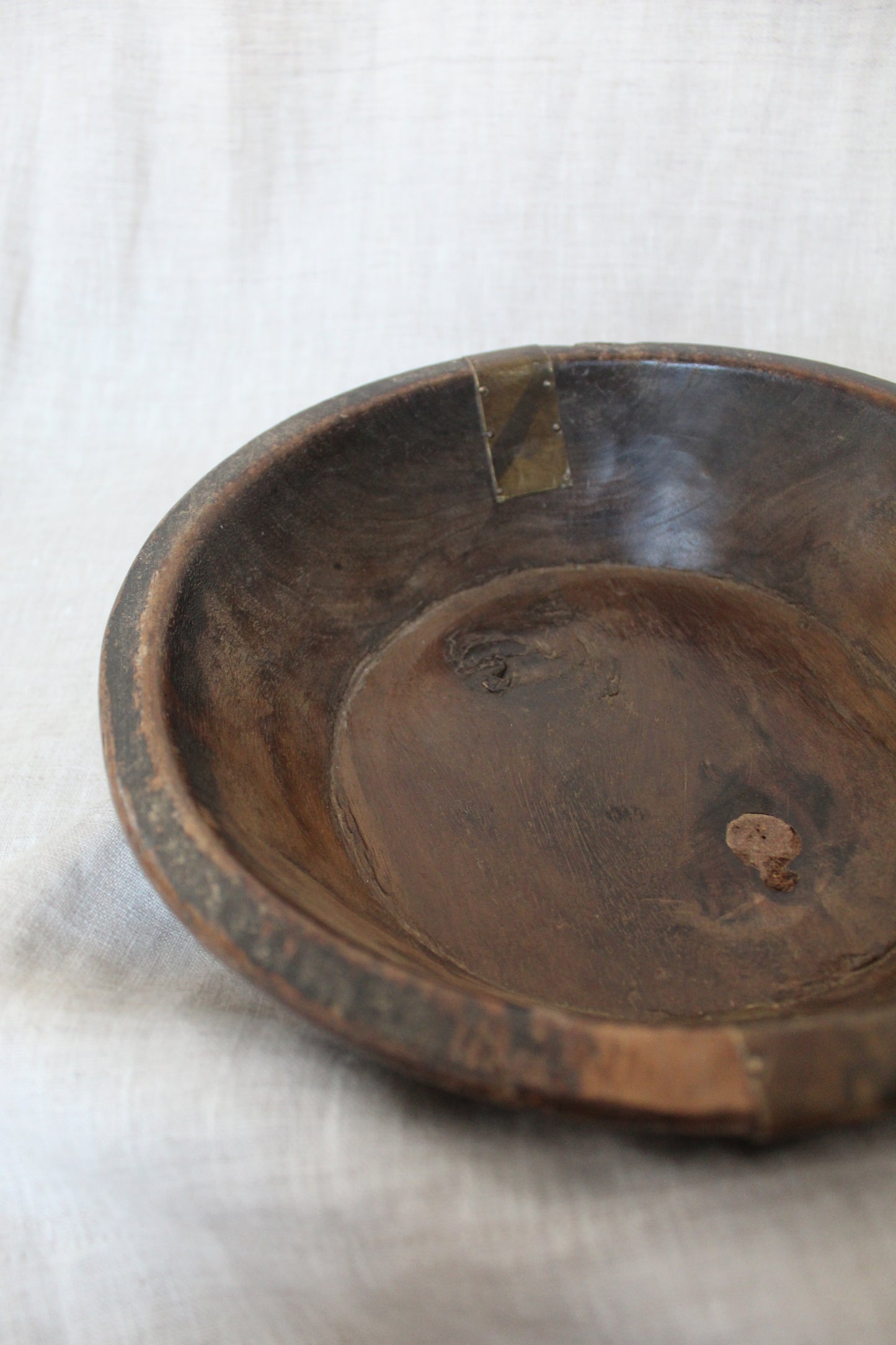 Close-up of an old wooden bowl on a white fabric background