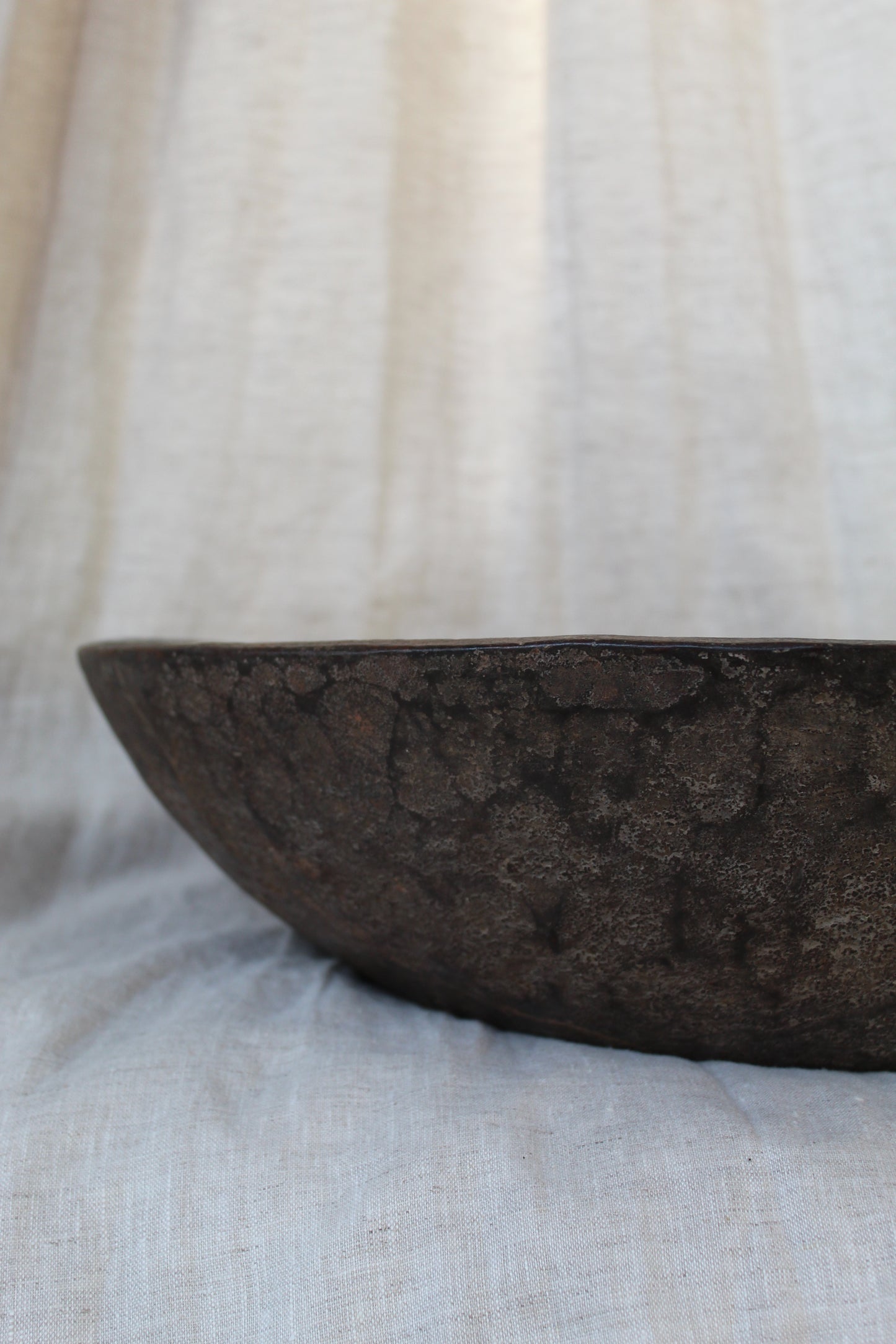 Close-up of a textured brown wood bowl on a light fabric background